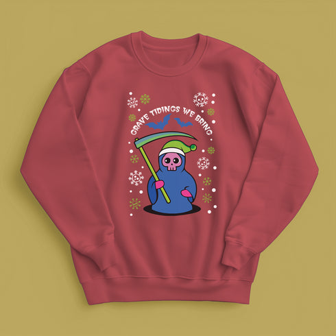 A holiday sweatshirt featuring a cute Grim Reaper holding a scythe, wearing a Santa hat. Above the character is the text "Grave Tidings We Bring," surrounded by festive snowflakes and holiday-themed designs. The combination of spooky and festive elements adds a humorous twist to traditional holiday attire.